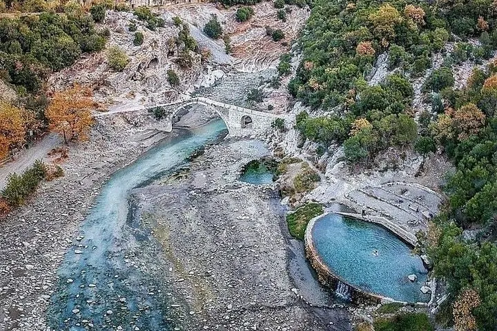 Luftaufnahme eines Flusses, einer Steinbrücke und natürlicher Thermalbecken.