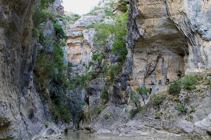Narrow canyon with steep rocky walls and a river flowing through it.
