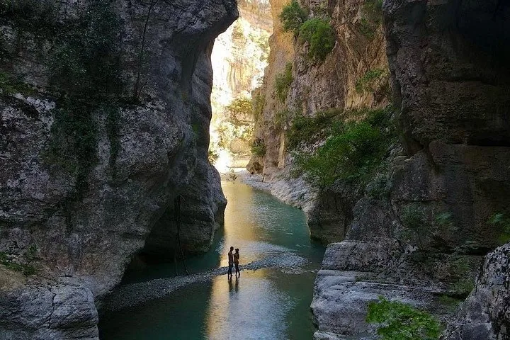 Couple standing in a river flowing through a narrow canyon.