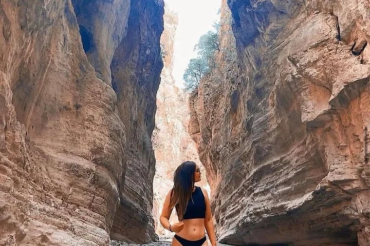 Mujer en bikini negro de pie en un cañón estrecho.