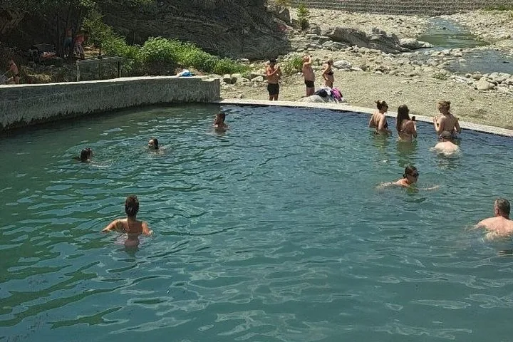 Menschen beim Schwimmen und Entspannen in einem natürlichen Thermalbecken.